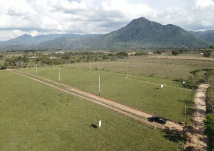 Aerial photograph of the El Volcán land in Ayapa, Yoro: open dirt streets and marker posts across green lots, a mountain behind.